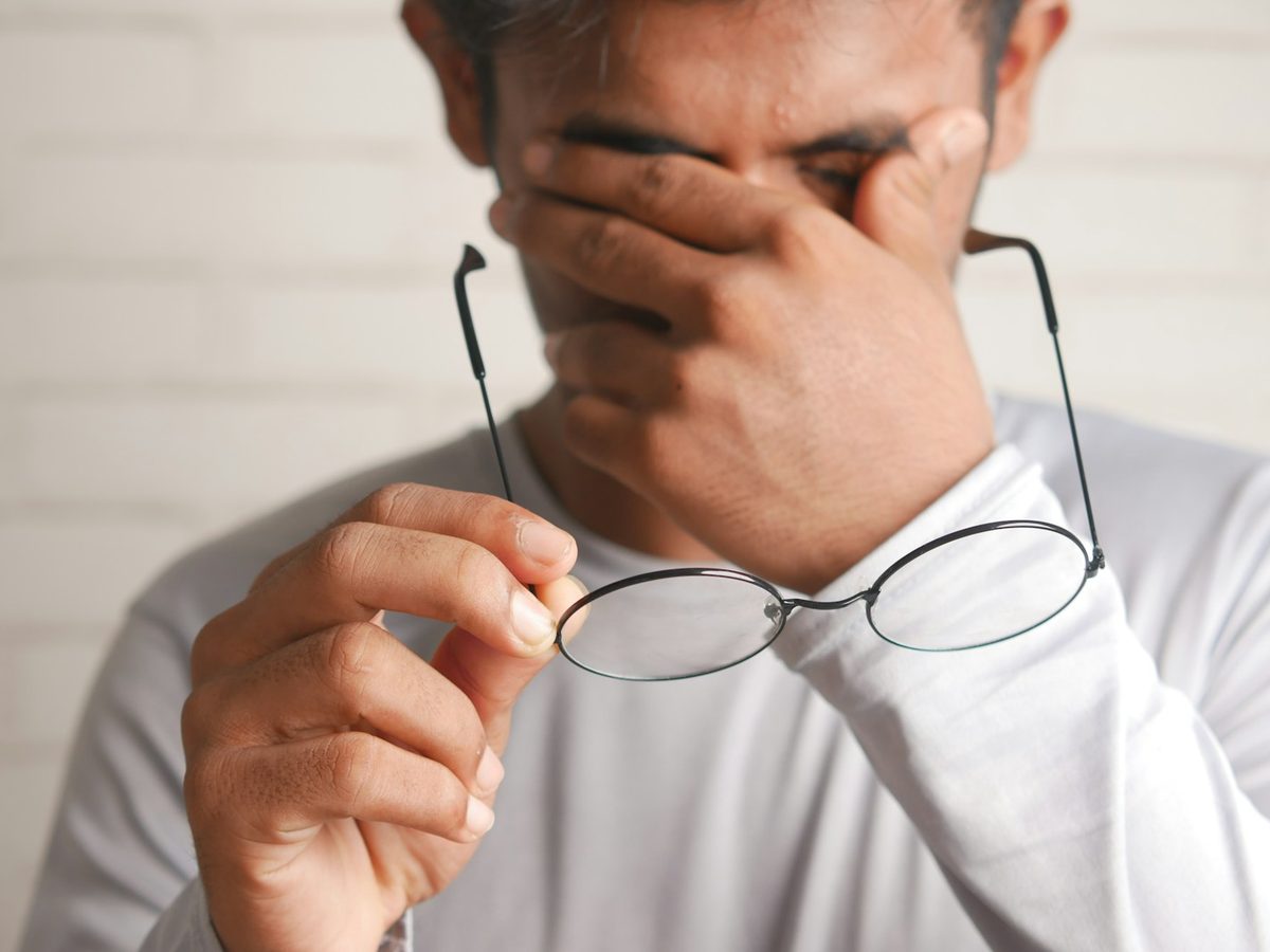 Homem com cansaço visual segurando os óculos